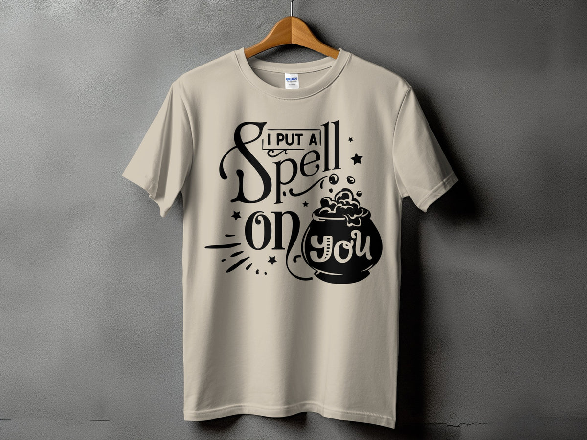Light tan t-shirt with black text "I PUT A SPELL on YOU" and a cauldron graphic.