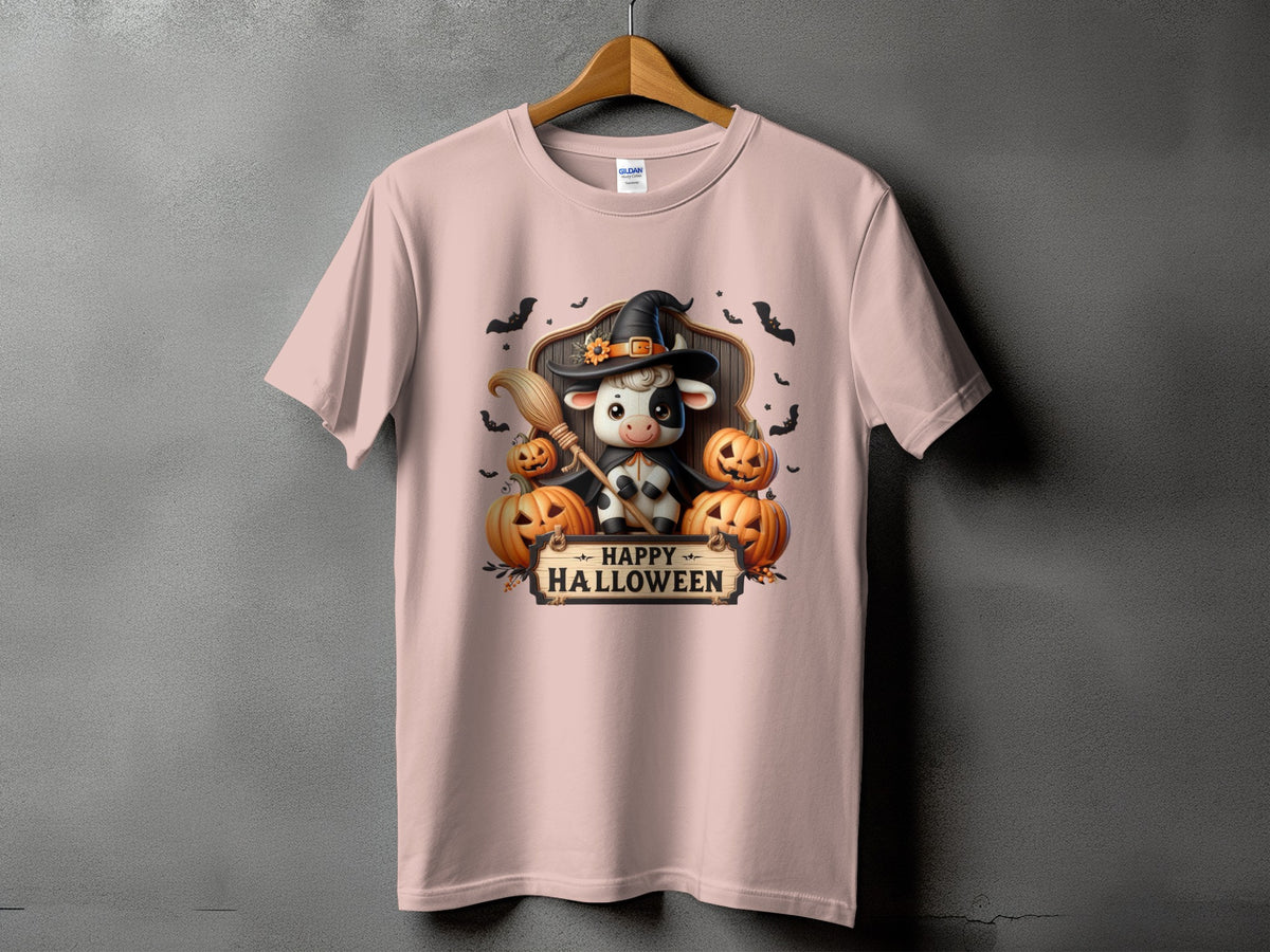 Pink t-shirt with a cow in a witch hat holding a broom, surrounded by pumpkins.