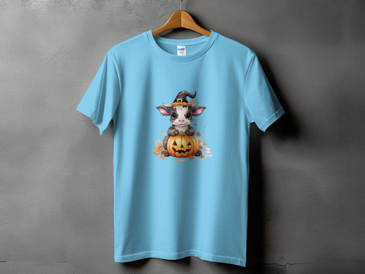 Light blue t-shirt with a cartoon calf wearing a witch hat on a pumpkin.