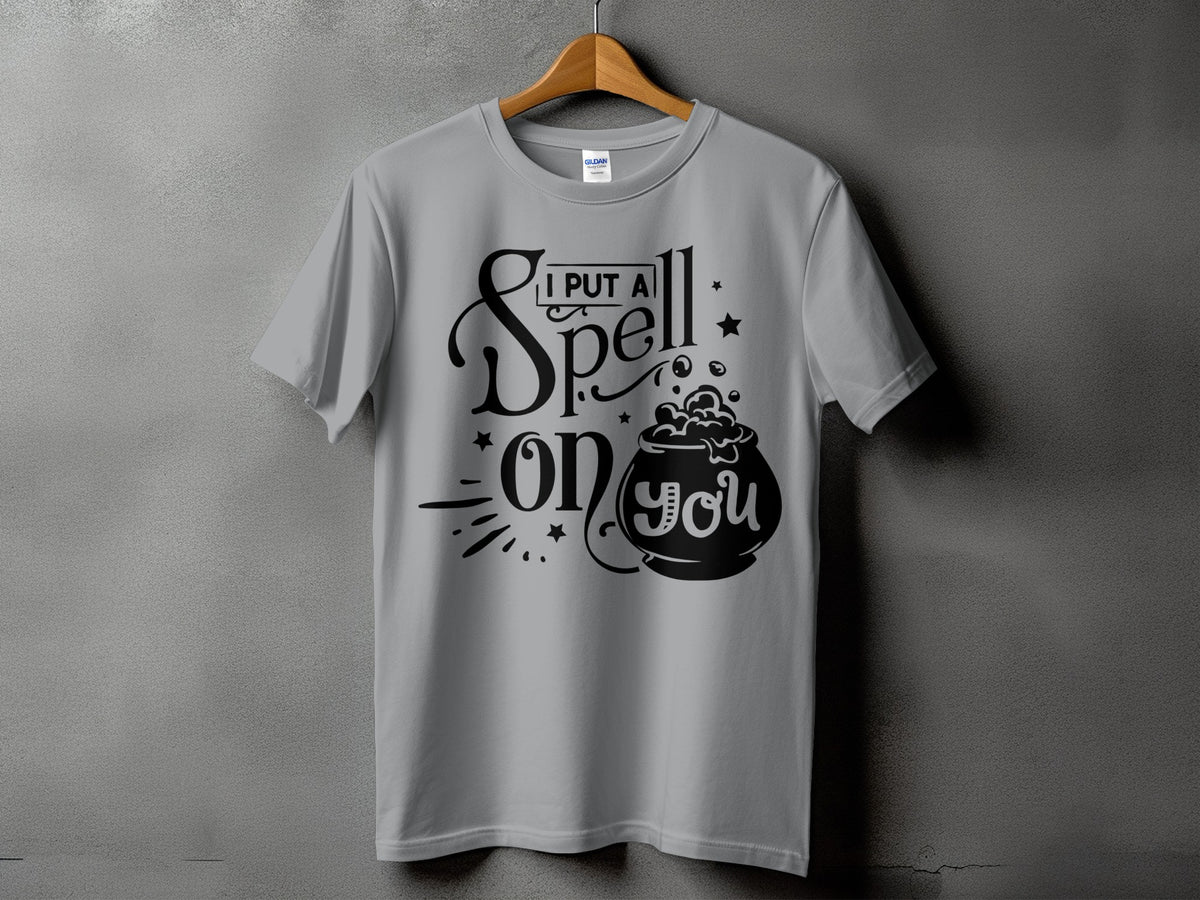 Gray t-shirt with black text and graphics that say "I put a spell on you" with a cauldron.