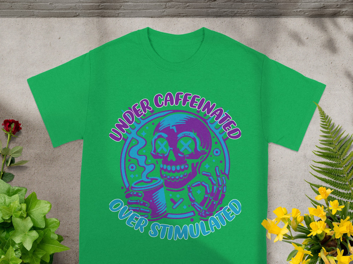 Green t-shirt with a purple and blue cartoon skull holding a coffee cup, text reads "UNDER CAFFEINATED OVER STIMULATED".