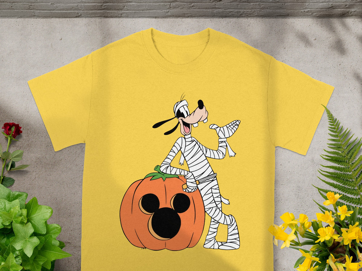 Goofy dressed as a mummy leaning on a Mickey Mouse pumpkin.