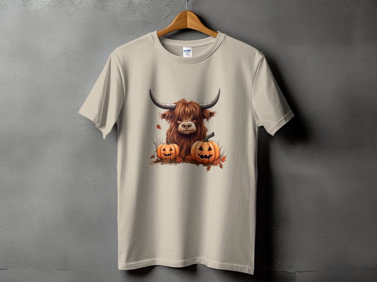 Tan t-shirt with a graphic of a Highland cow and two jack-o'-lanterns.