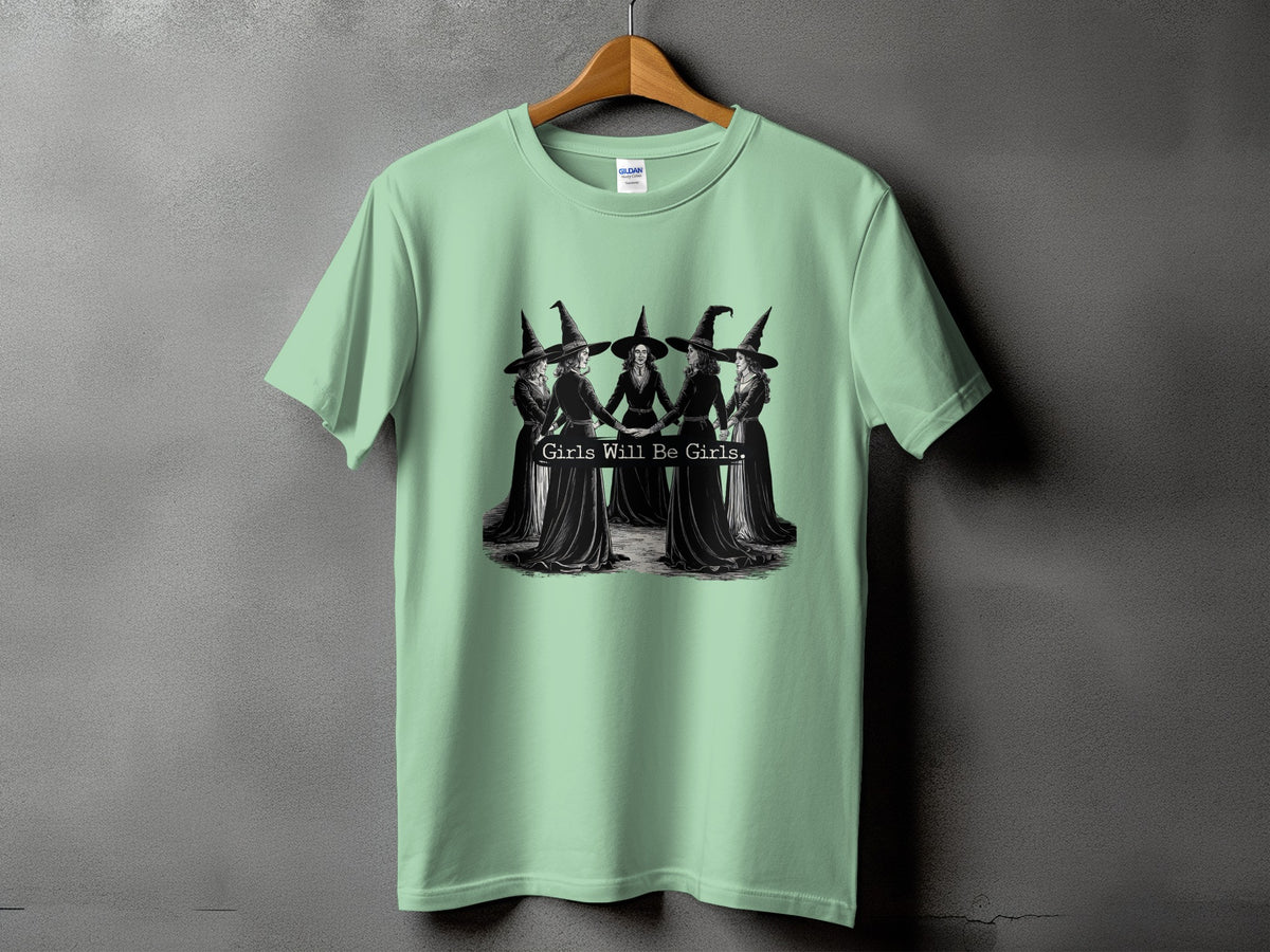 Light green t-shirt with black graphic of five witches holding hands with text "Girls Will Be Girls."
