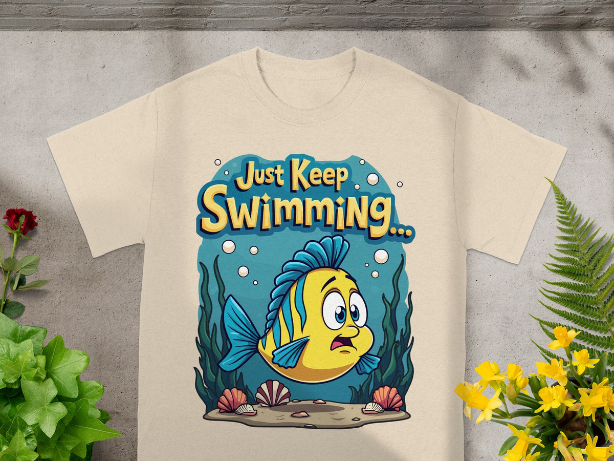 Yellow and blue fish with text "Just Keep Swimming..." on a tan t-shirt.