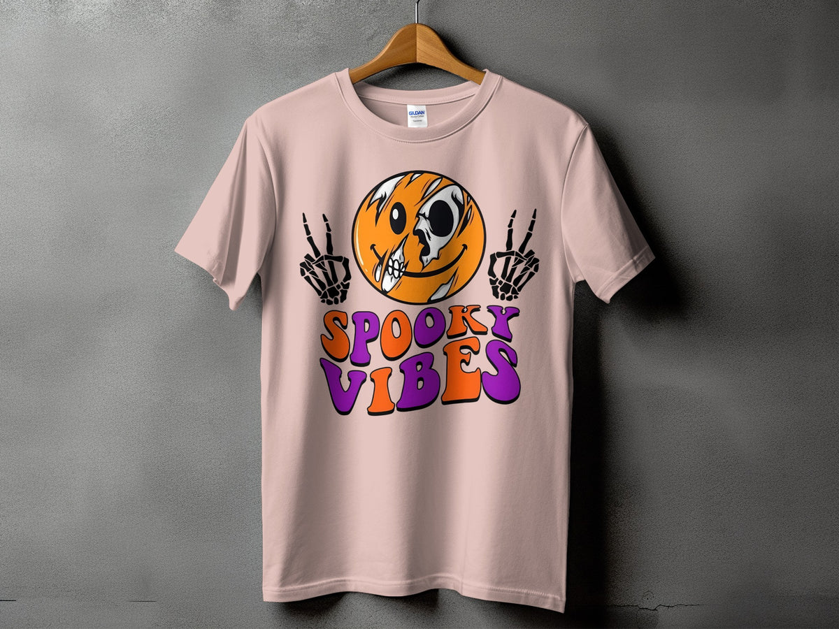 Pink t-shirt with a skull-faced smiley and skeleton hands, reading "Spooky Vibes".