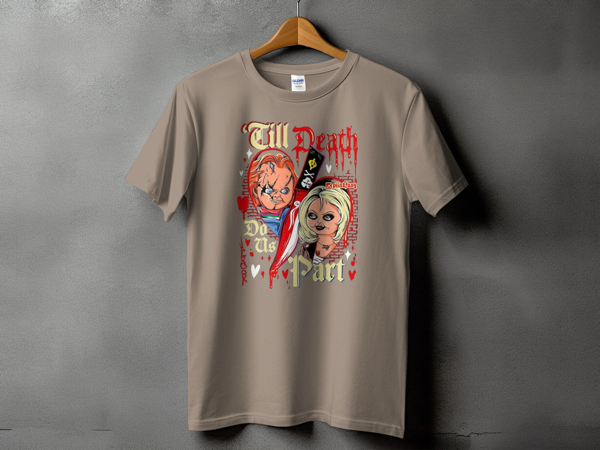 A sandy tan short-sleeve t-shirt featuring a Chucky and Tiffany graphic and text reading "Till Death Do Us Part".
