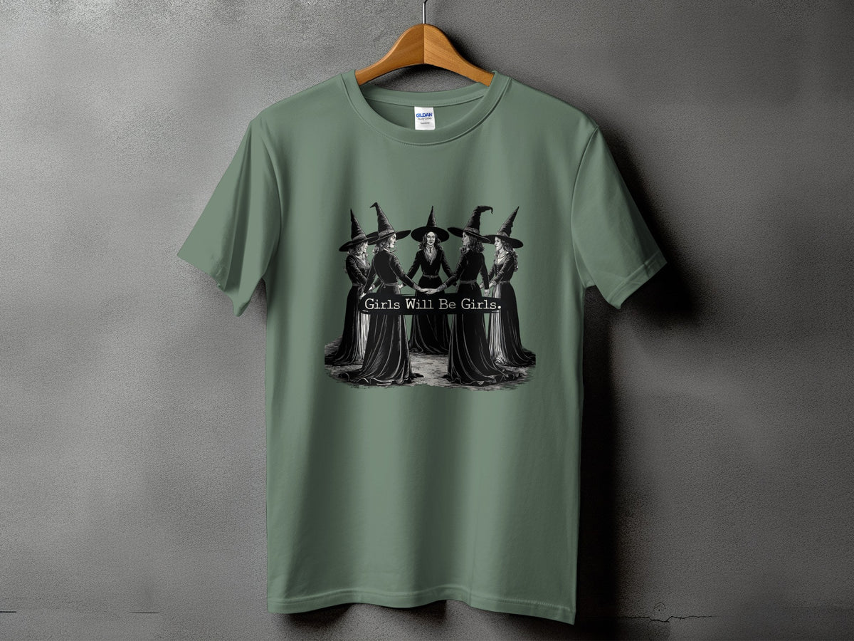 Green t-shirt with a graphic of witches holding hands and text "Girls Will Be Girls".