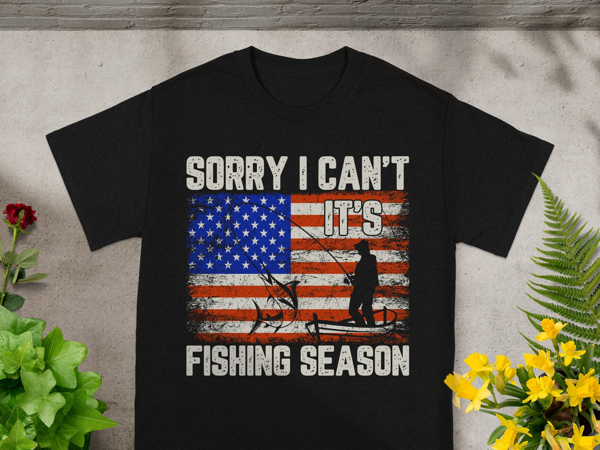 Black t-shirt with distressed American flag, fishing silhouette, and text "Sorry I Can't It's Fishing Season".