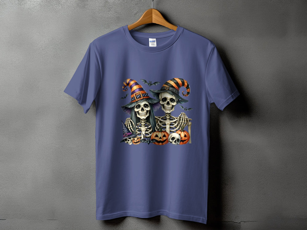Two skeletons in witch hats with bats and pumpkins on a purple t-shirt.