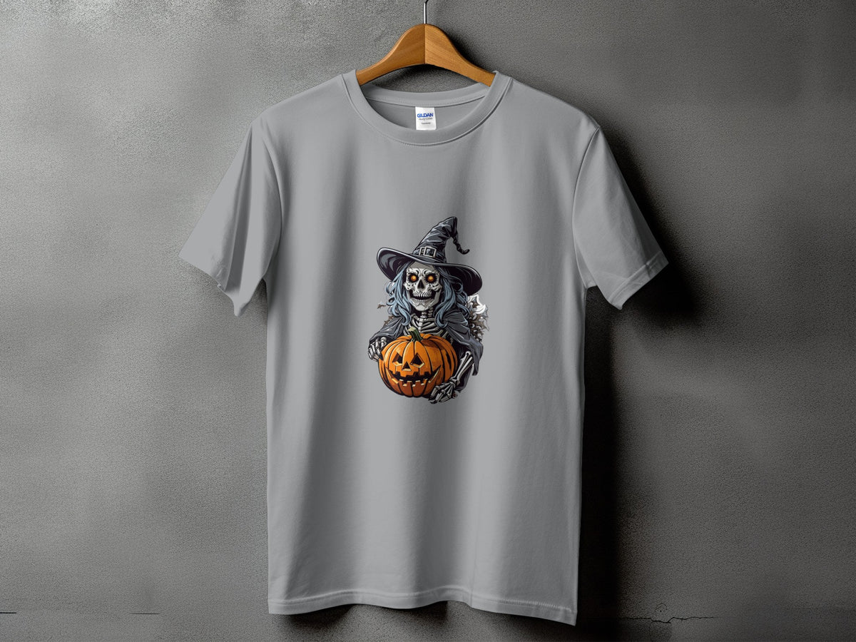 Skeleton in witch hat holds carved pumpkin on grey t-shirt.