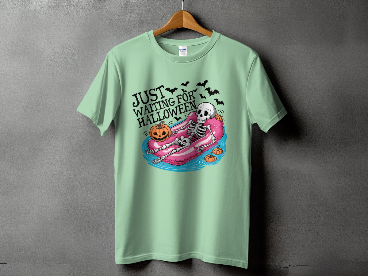 Green t-shirt with skeleton on inflatable tube and text "JUST WAITING FOR HALLOWEEN".