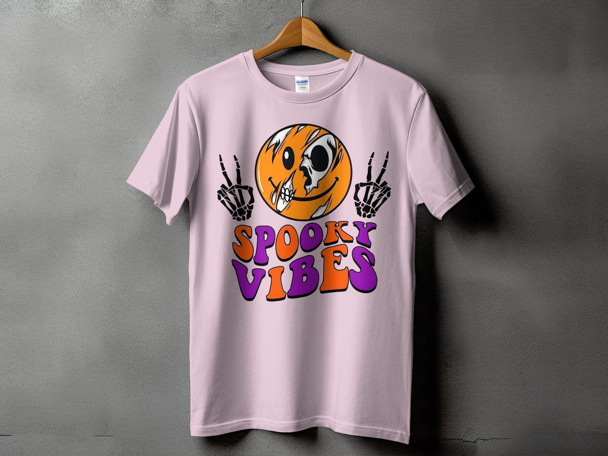 Pink t-shirt with spooky smiley face and skeleton hands, text reads "Spooky Vibes".