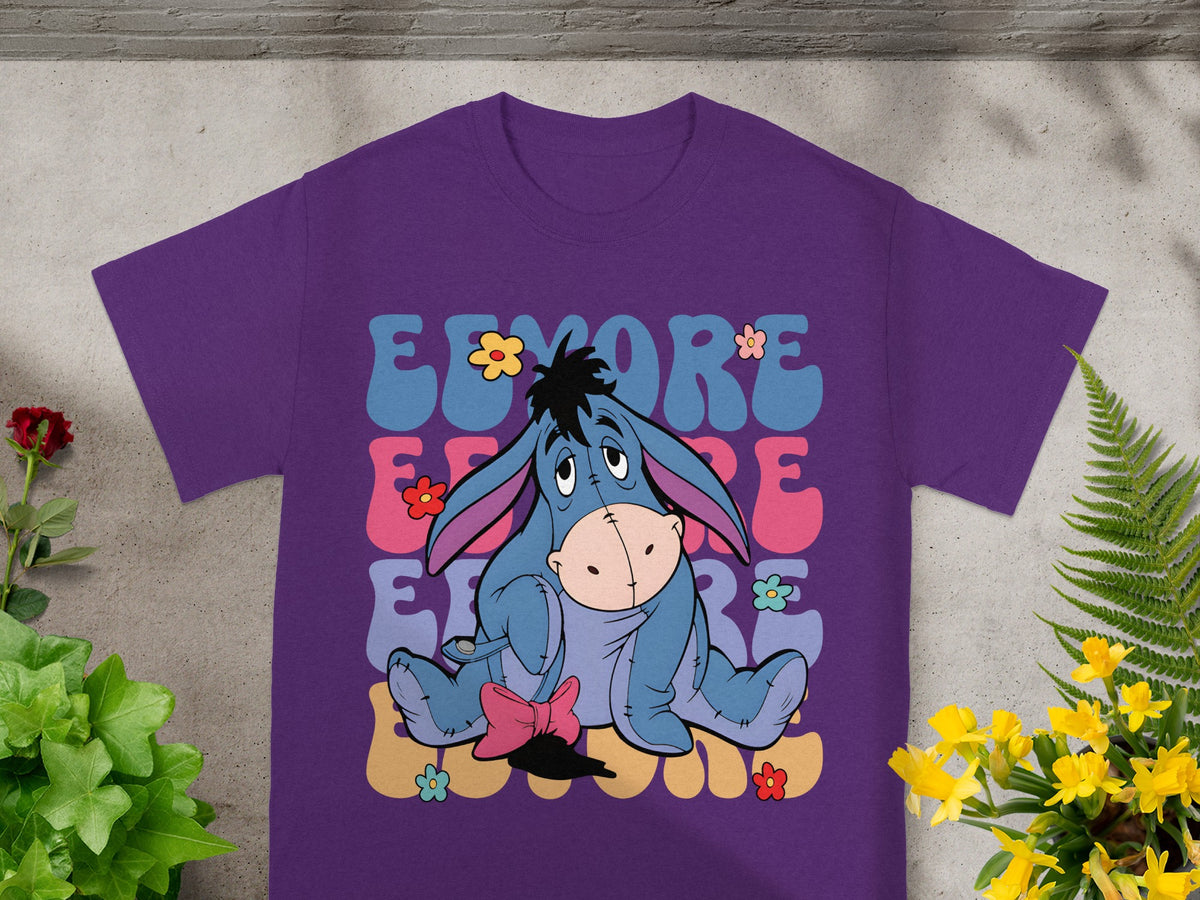 Purple t-shirt with Eeyore sitting among colorful flowers and text.